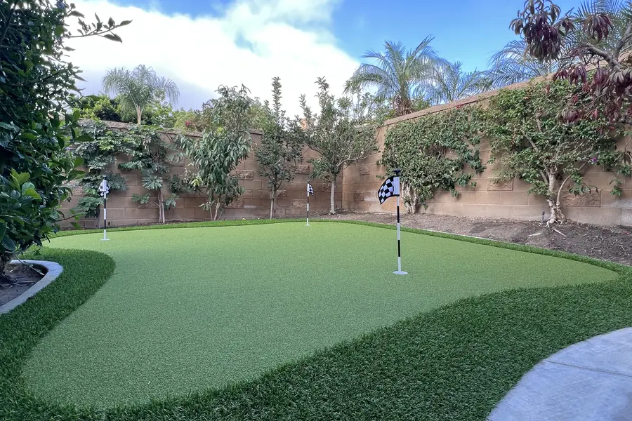 Backyard putting green beside a patio and landscaped slope
