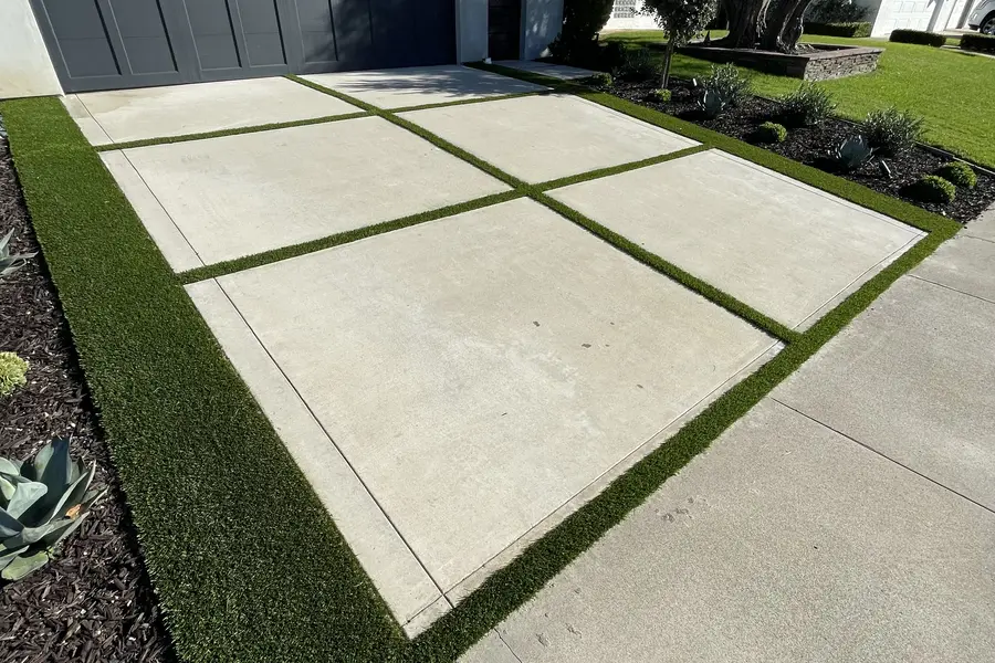 Clean artificial turf ribbons installed between driveway pavers