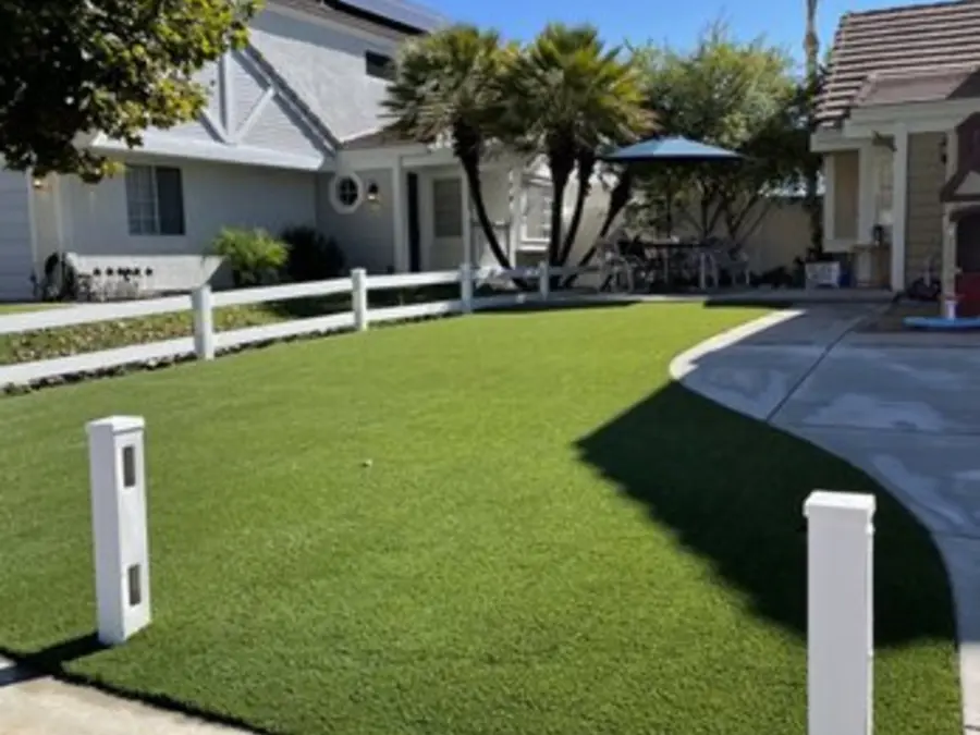 Finished front lawns along a white fence line